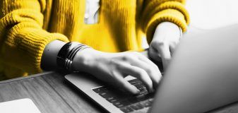 Close-up of young programmer typing codes to work with software while sitting at his workplace at office